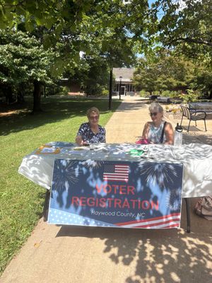 Two women sitting at a voter registration table outdoors on National Voter Registration Day.
