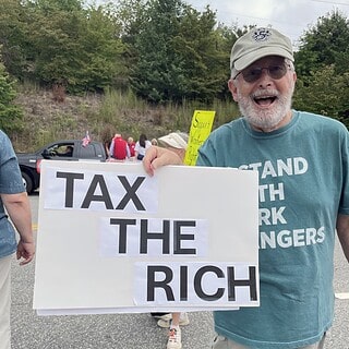 Man holding a sign that says 'Tax the Rich' at a protest in Haywood.