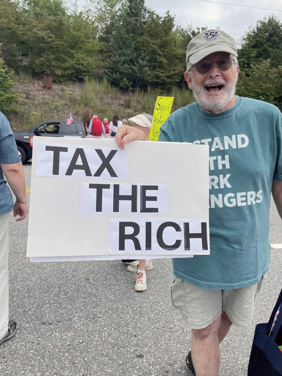 Man holding a sign that says 'Tax the Rich' at a protest in Haywood.