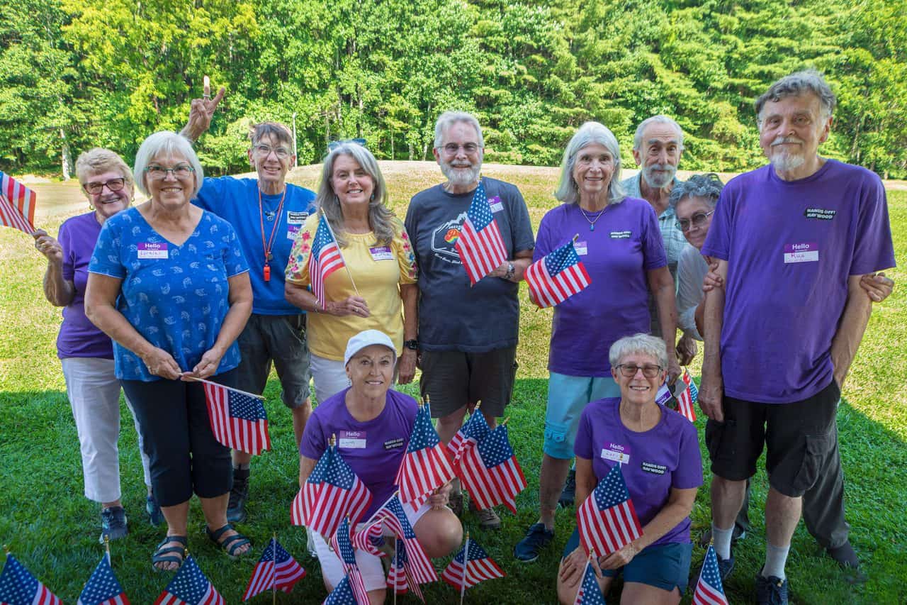 Group of diverse people holding American flags outdoors for Hands Off! Haywood event.